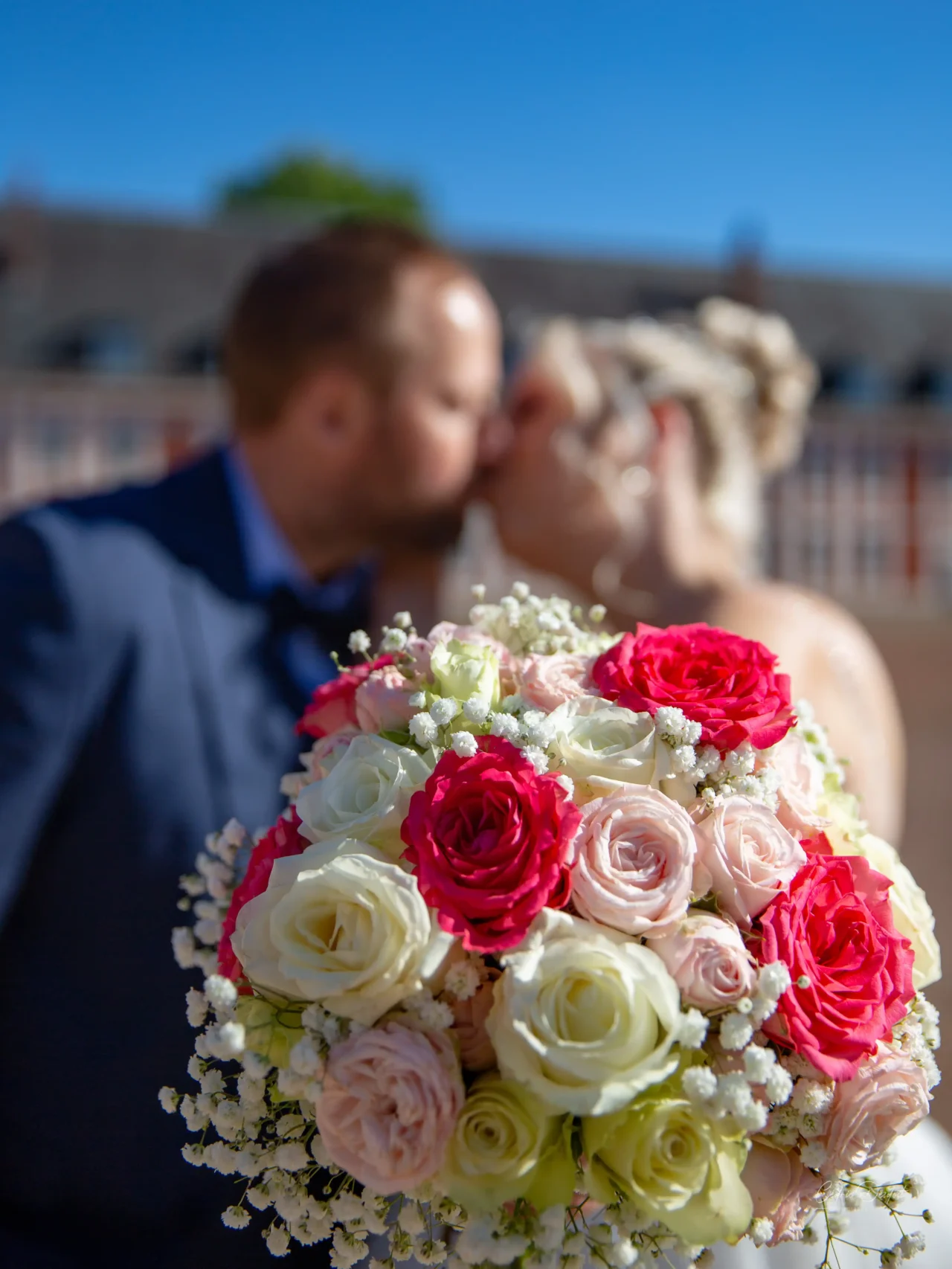 Mariés qui s’embrassent derrière le bouquet de la mariée, mariage à la Citadelle d’Arras