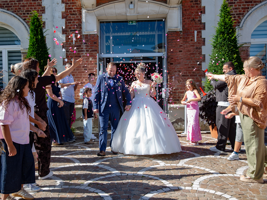 Sortie des mariés sous les confettis devant un bâtiment de la Citadelle d’Arras, mariage à Arras